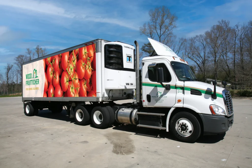 White refrigerated semi-truck with green trim displaying fresh tomatoes, equipped with Thermo King cooling system for commercial food distribution.