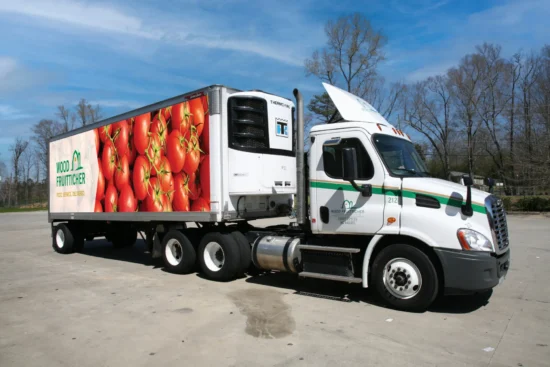 White refrigerated semi-truck with green trim displaying fresh tomatoes, equipped with Thermo King cooling system for commercial food distribution.